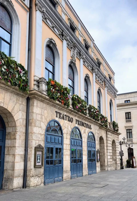 Puertas azules de medio punto y balcones del Teatro Principal engalanados con guirnaldas florales festivas