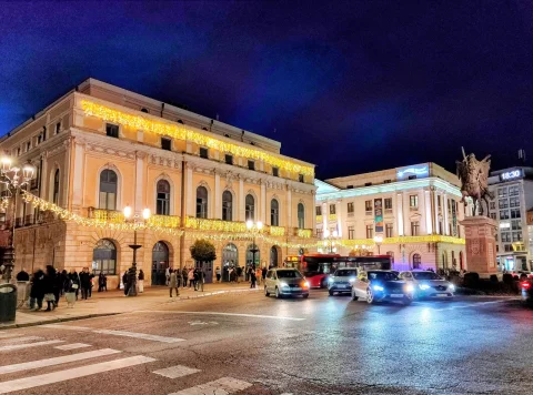 Vista nocturna de la plaza del Mío Cid y el Teatro Principal con iluminación navideña y tráfico urbano