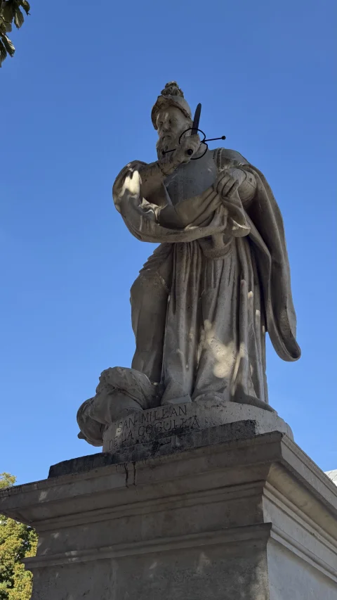 Monumento a San Millán de la Cogulla con ropajes talares, espada y relieve del nombre en la base