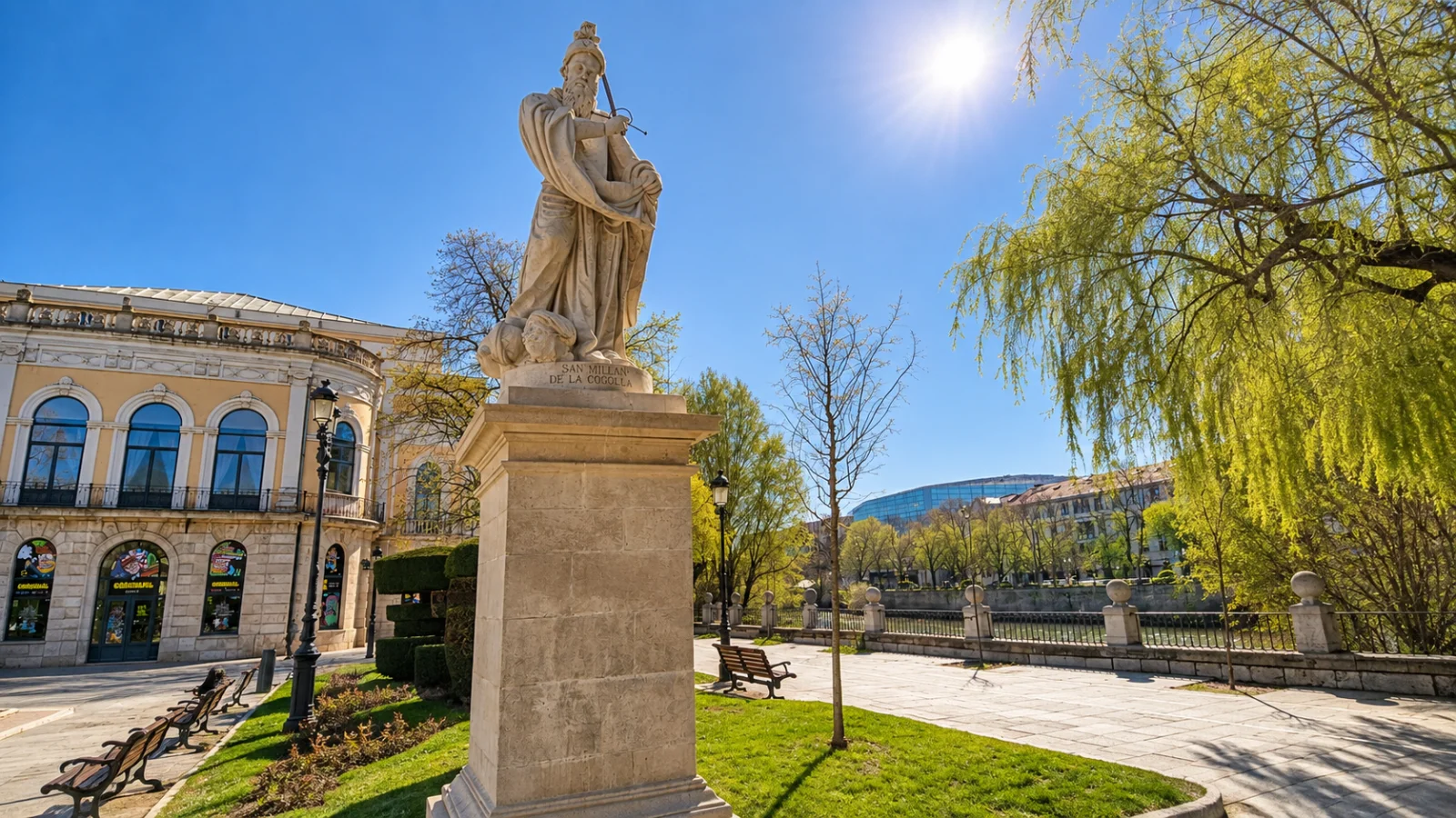Estatua de San Millán de la Cogulla sobre alto pedestal de piedra con el Teatro Principal y el río Arlanzón de fondo