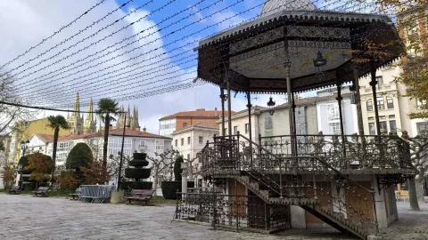 Templete de forja con escaleras y luces suspendidas con los pináculos de la catedral de fondo