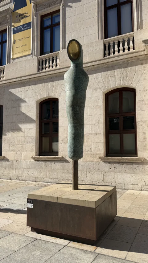 Detalle de escultura de bronce verdoso con abertura ovalada dorada en la parte superior