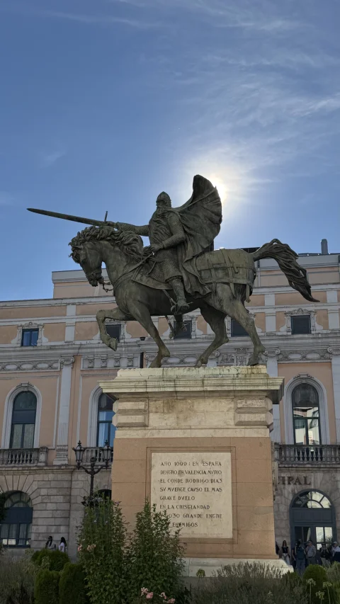 Silueta a contraluz de la estatua ecuestre del Cid Campeador sobre la placa en verso del pedestal