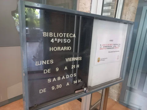Cartelera informativa con los horarios de apertura y ubicación en 4º piso de la Biblioteca