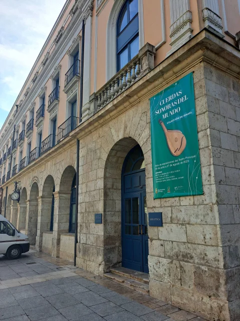 Puerta azul de entrada en arco de medio punto bajo lona verde cultural en la fachada del Teatro Principal