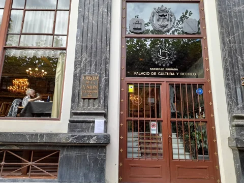 Entrada al Círculo de la Unión con puerta de rejería metálica, placa conmemorativa de 1881 y escudo tallado