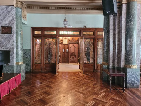 Portón interior de madera noble con vidrieras artísticas emplomadas y columnas de mármol veteado