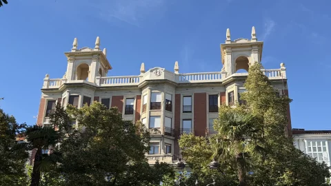 Remate superior con torreones clasicistas y balaustrada del edificio del Espolón sobre las copas de los árboles