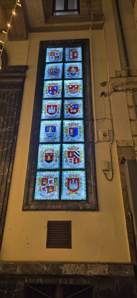 Vidriera vertical iluminada con los escudos heráldicos de los partidos judiciales y villas de Burgo