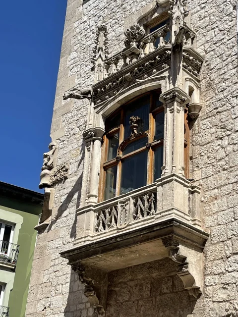 Balcón volado de la torre con tracería gótica en la balaustrada, pilastras labradas y adorno superior en piedra