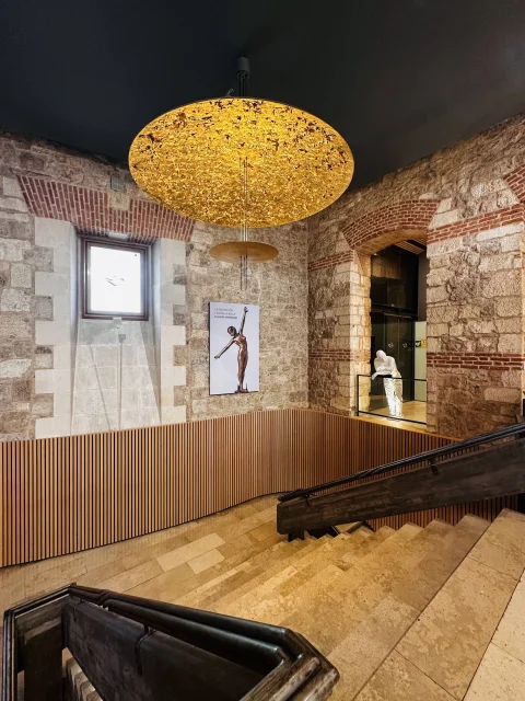 Escalera interior con iluminación contemporánea y muros de piedra