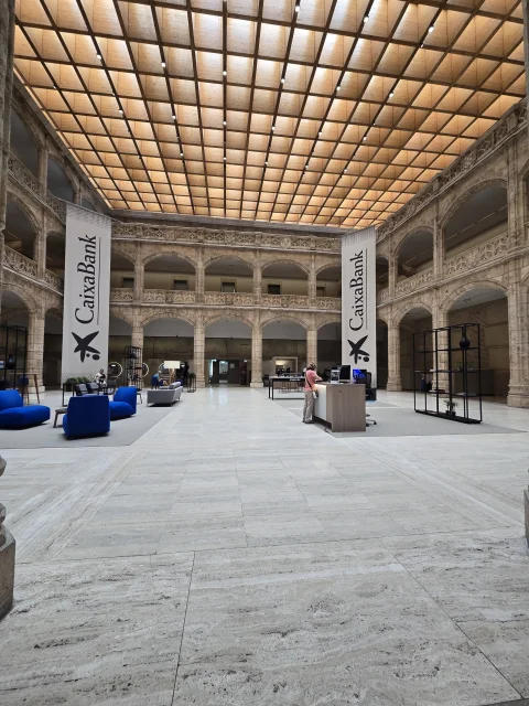 Gran patio interior de tres niveles con galerías de arcos, cubierto por un techo acristalado reticulado