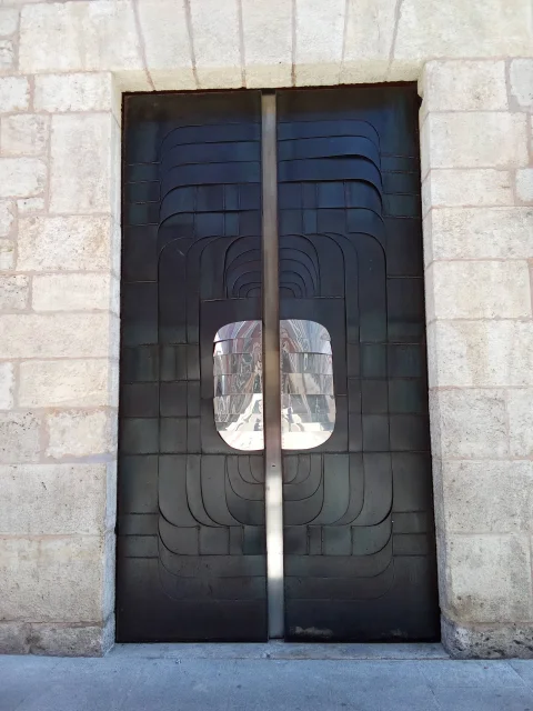 Puerta metálica de diseño contemporáneo en la fachada de piedra
