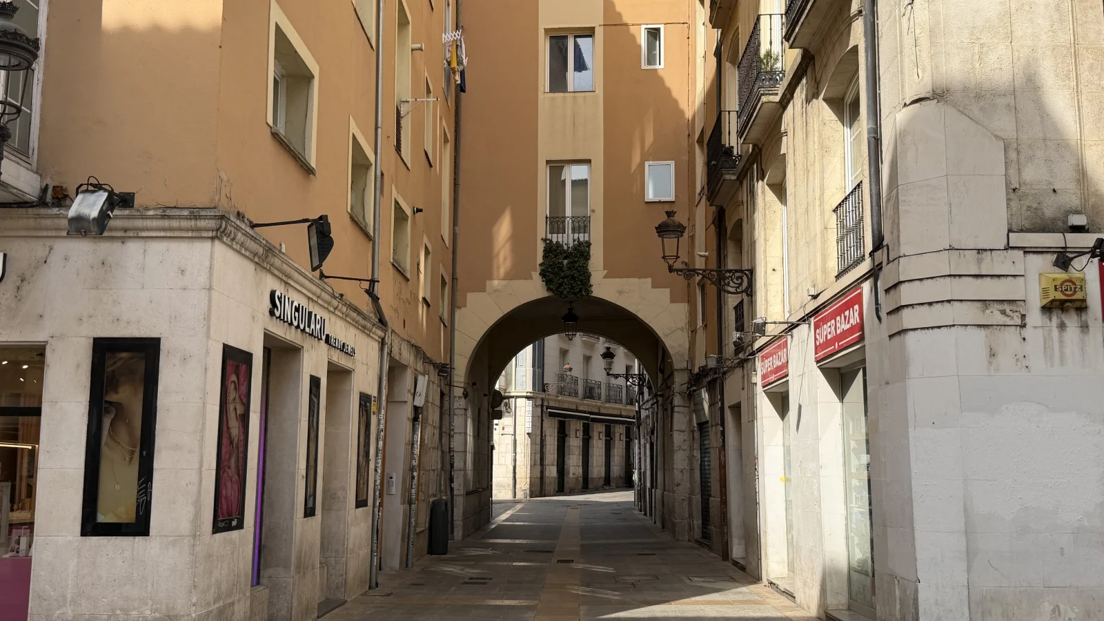Encuadre del arco de piedra integrado en la arquitectura urbana entre comercios y viviendas tradicionales