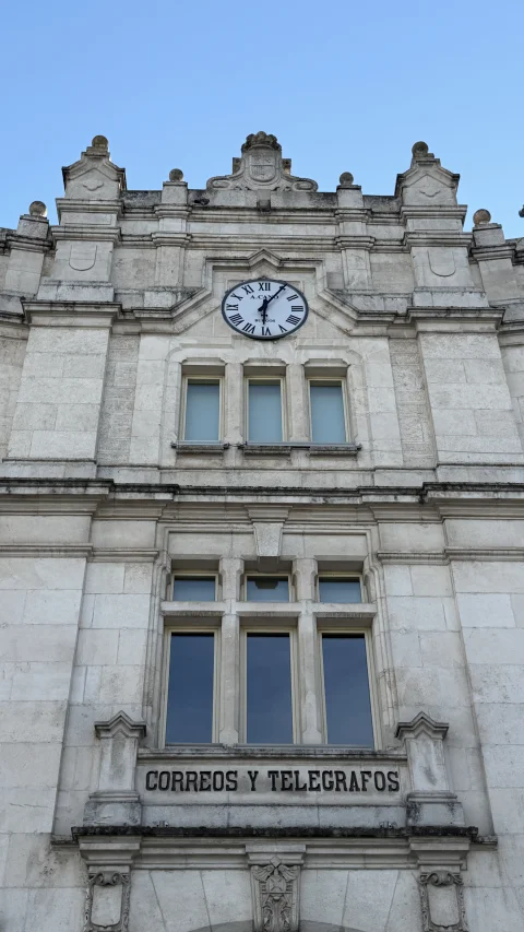 Plano medio de la fachada de piedra con el reloj analógico, ventanales y el rótulo