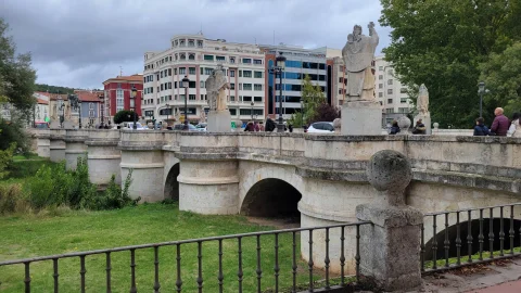 Arquería de sillería de piedra del Puente de San Pablo con estatuas cidianas y edificios del paseo al fondo