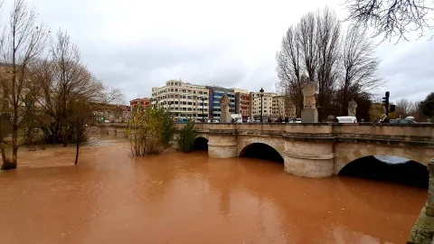 Crecida y aguas bravas arcillosas del río Arlanzón bajo los arcos de piedra del Puente de San Pablo