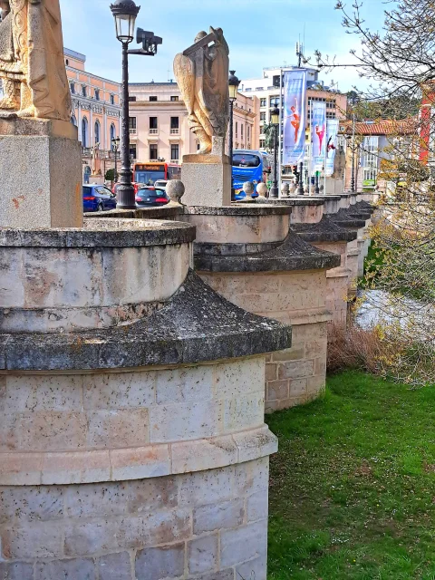 Hilera de contrafuertes y tajamares de sillería con esculturas cidianas, farolas y tráfico rodado