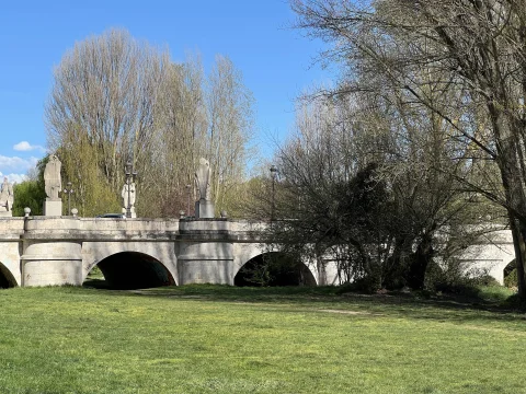 rquería de piedra y esculturas del ciclo cidiano recortadas entre la arboleda y el césped fluvial