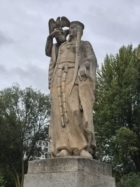 Estatua de piedra de Doña Jimena con largas trenzas y una paloma sobre el hombro