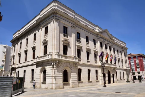 Fachada esquinera de piedra clara del Palacio de la Diputación con farola clásica y plaza despejada
