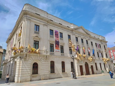 Fachada esquinera de piedra clara del Palacio de la Diputación con farola clásica y plaza despejada