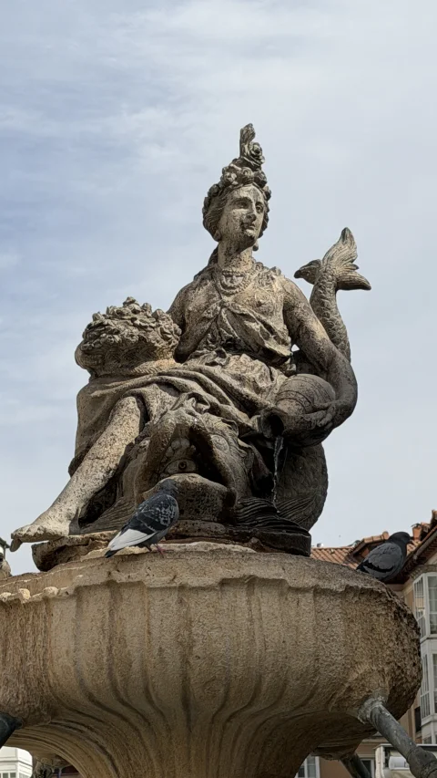 Primer plano de la estatua clásica tallada en piedra con palomas posadas