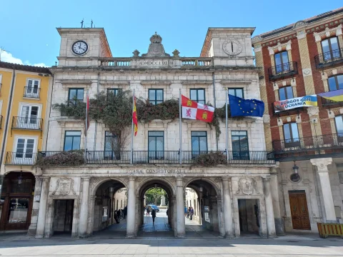 Ayuntamiento de Burgos con balcones decorados con plantas, banderas oficiales y relojes simétricos en sus torres