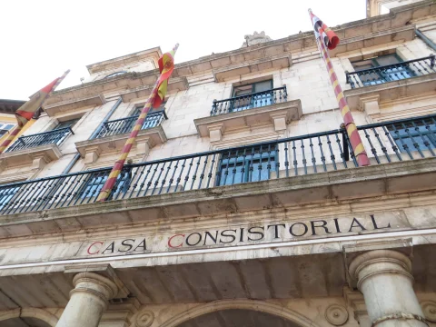 Plano contrapicado de la inscripción CASA CONSISTORIAL y balconadas con banderas