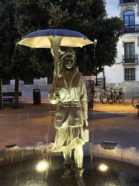 La fuente iluminada de noche por los focos del pilón, con las cortinas de agua cayendo del paraguas