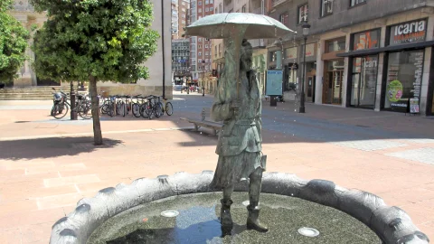 La fuente de día desde la plaza peatonal, con el pilón y la figura bajo el paraguas