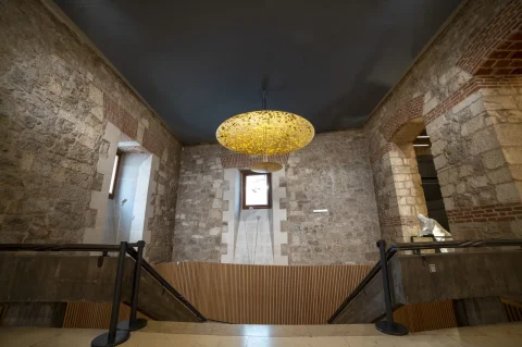 Escalera y vestíbulo con muros de piedra e iluminación de diseño