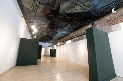 Sala de exposiciones diáfana con paneles divisores y techo de madera entablada