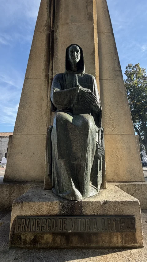 Escultura de bronce de Francisco de Vitoria sentado con hábito y capucha