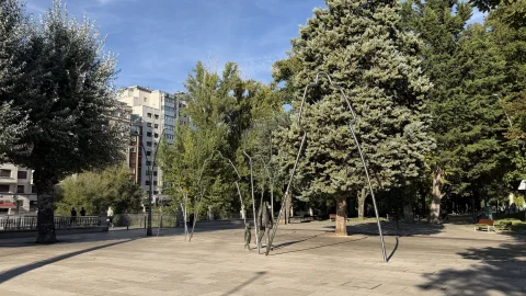 Vista en perspectiva de la escultura monumental Evolución con arcos metálicos tubulares y figuras