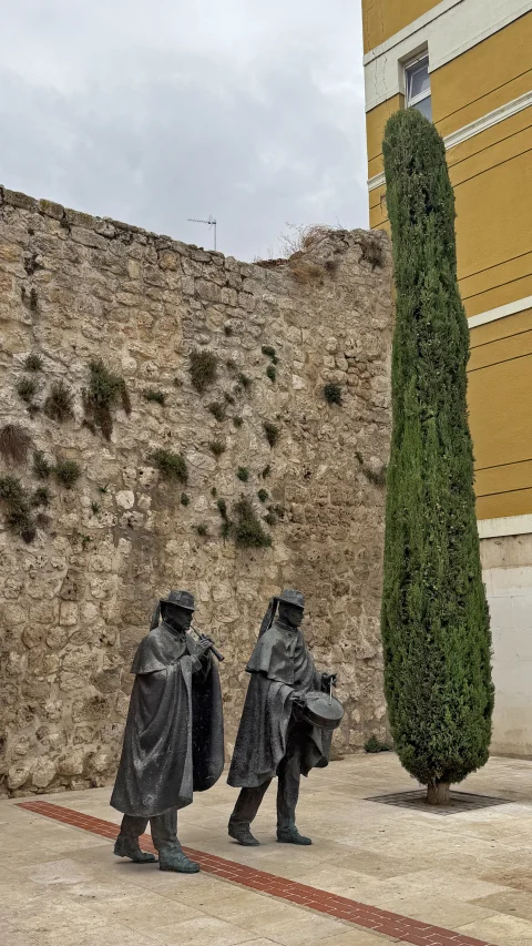 Escultura de Los Dulzaineros en Burgos ante el muro de piedra de la calle San Lesmes