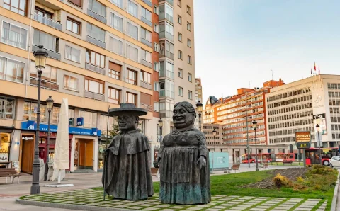Escultura de Los Gigantillos en Burgos vista de frente sobre el damero de losa y cesped