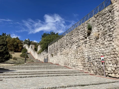 Lienzo de la muralla medieval de piedra que asciende junto a una amplia escalinata