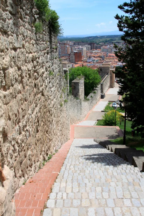 Vista descendente de las escaleras junto a la muralla de piedra con el paisaje urbano de Burgos