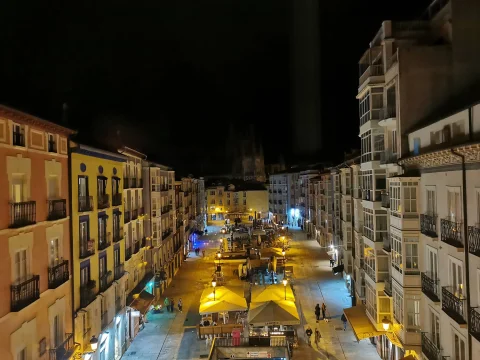 Vista aérea nocturna de la plaza con iluminación cálida en los edificios tradicionales