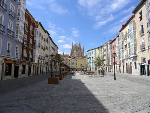 Vista en perspectiva de la plaza peatonal flanqueada por edificios residenciales de colores