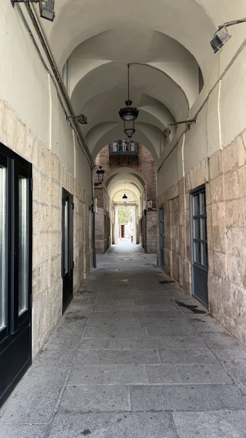 Vista en profundidad del pasadizo peatonal con arcos de medio punto, bóvedas de cañón y faroles de hierro