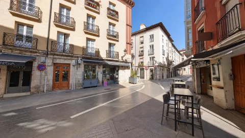 Vista en perspectiva de la calle peatonal San Gil con mesas y taburetes de terraza exterior