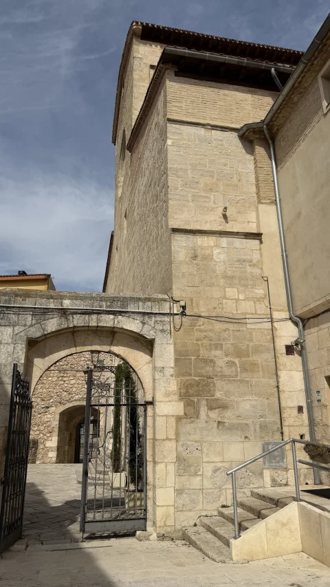 Acceso con reja metálica junto a la base de la torre de piedra y pequeñas escaleras de acceso