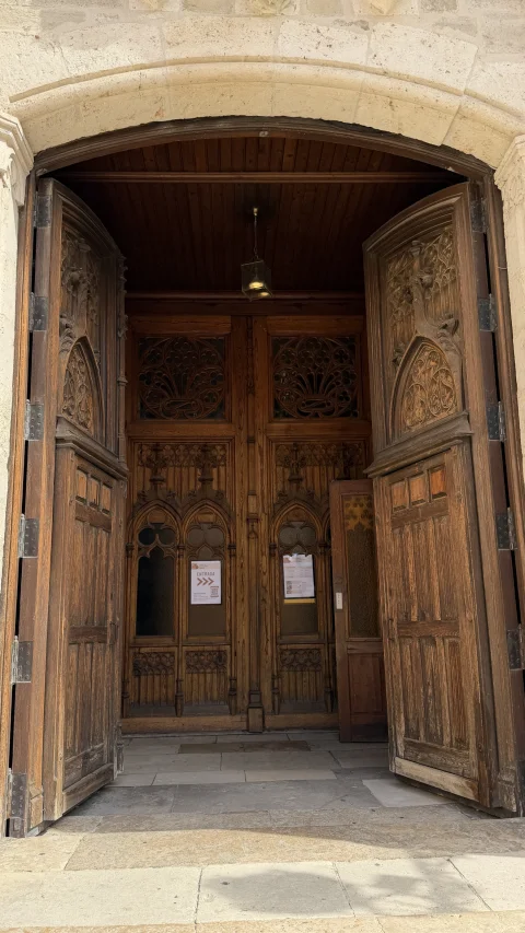 Detalle de los grandes portones de madera de estilo gótico tallados y abiertos hacia el interior