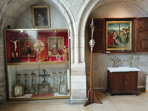 Vitrina de orfebrería y pinturas y tríptico de la Piedad sobre un mueble de madera