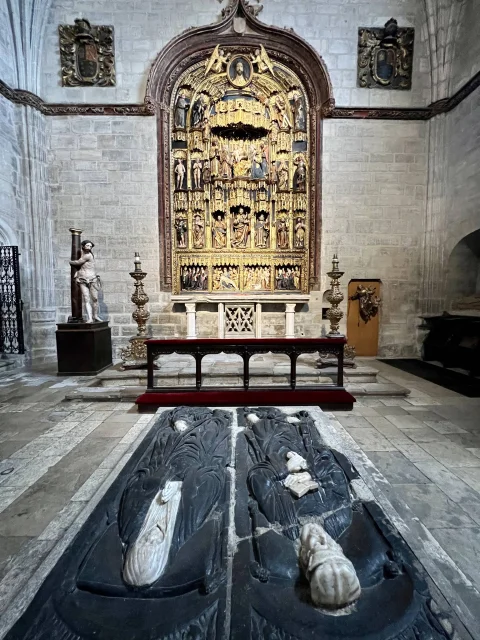 Vista frontal del retablo hispanoflamenco de madera dorada con el sepulcro yacente en primer plano