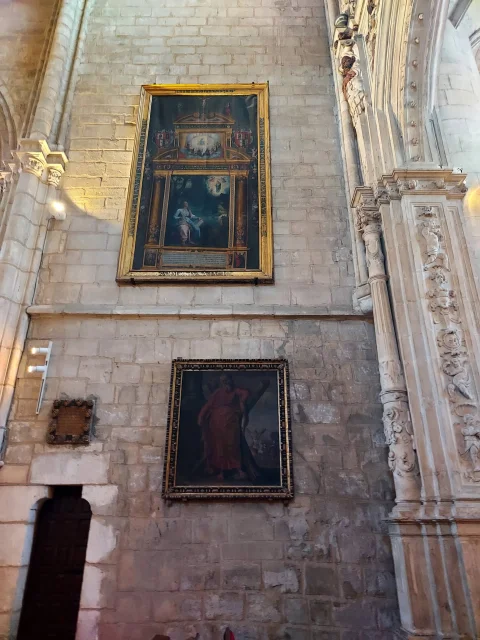 Lienzos al óleo con marcos dorados instalados sobre el muro de piedra de la nave de la iglesia