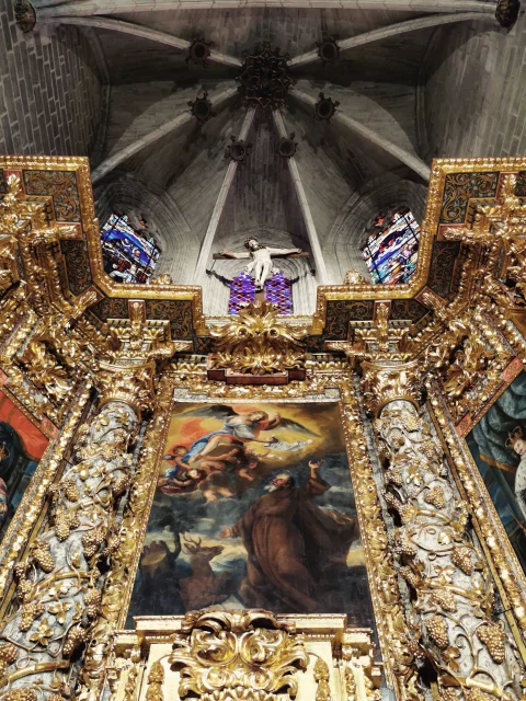 Retablo mayor mostrando las columnas recubiertas de pan de oro y las nervaduras de la bóveda gótica