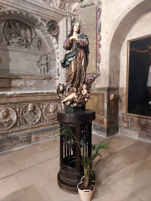 Imagen de la Inmaculada Concepción sobre peana de madera junto a la lápida conmemorativa y arcosolio